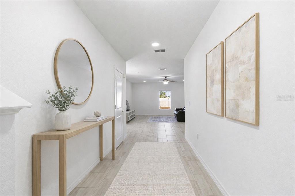 A modern kitchen features white cabinetry, a central island with bar stools, and stainless appliances — 35132 ACKLEY TRACE, ZEPHYRHILLS, FL
