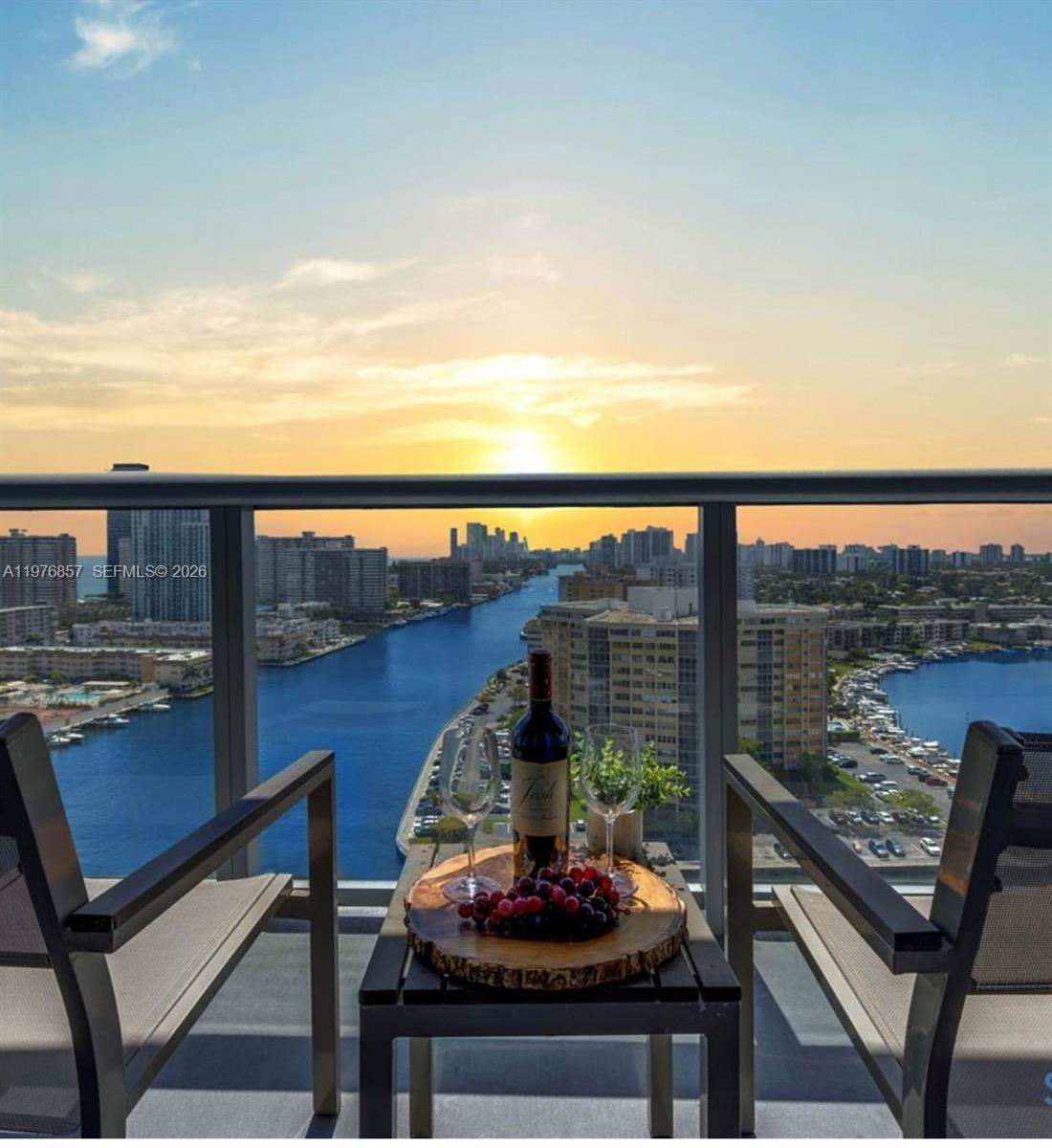 A balcony with two chairs and a table overlooking a canal at sunset — 2602 E Hallandale Beach Blvd # R3009, Hallandale Beach FL 33009, HALLANDALE BEACH, FL