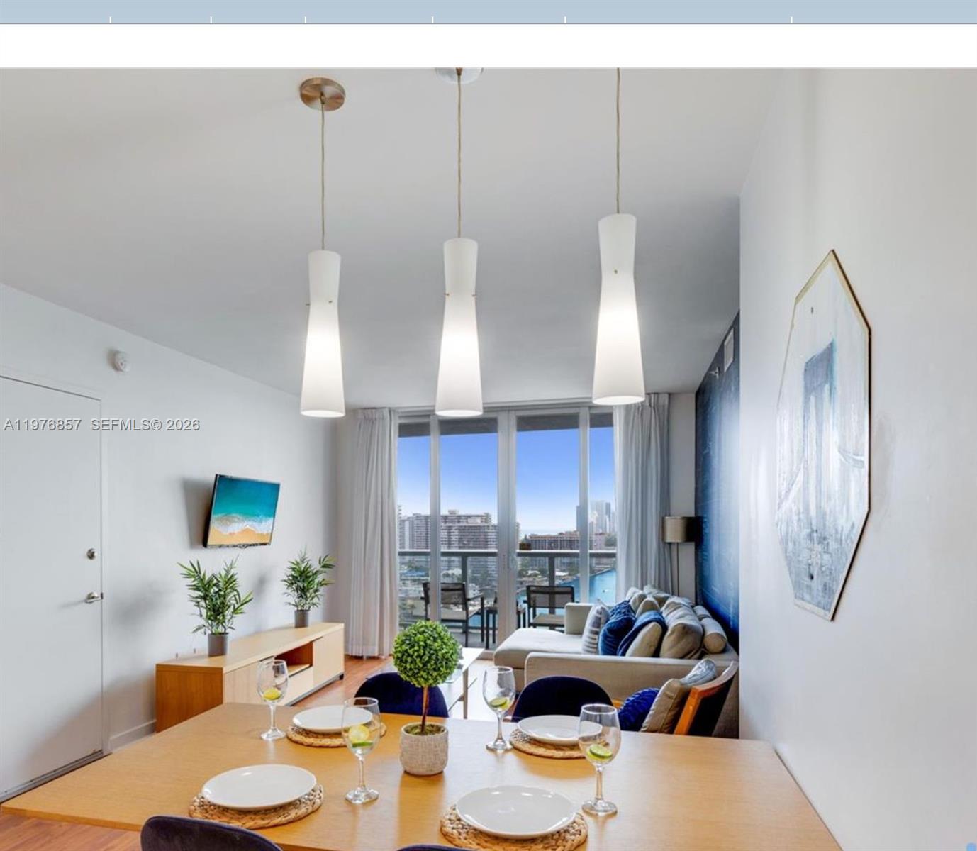 A dining area with a wooden table leads into a living room with balcony views — 2602 E Hallandale Beach Blvd # R3009, Hallandale Beach FL 33009, HALLANDALE BEACH, FL