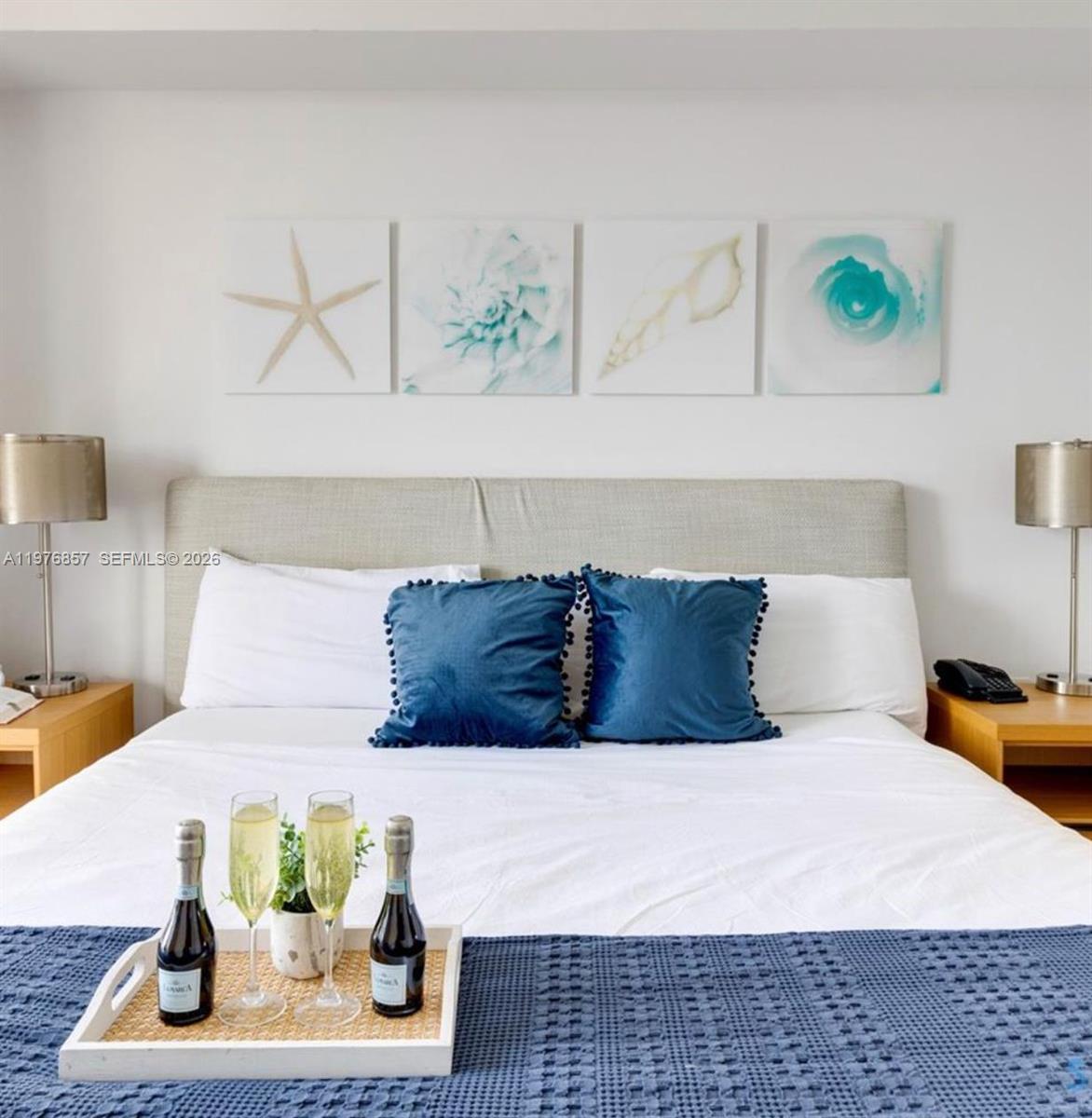 A bedroom features a bed with blue accent pillows and a tray holding two champagne bottles — 2602 E Hallandale Beach Blvd # R3009, Hallandale Beach FL 33009, HALLANDALE BEACH, FL
