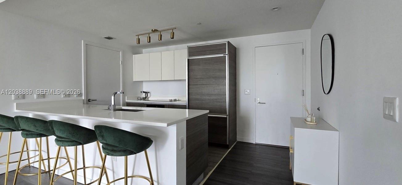 A modern kitchen features a white island with green barstools and dark wood cabinetry — 1100 S Miami Ave # 3808, Miami FL 33130, MIAMI, FL