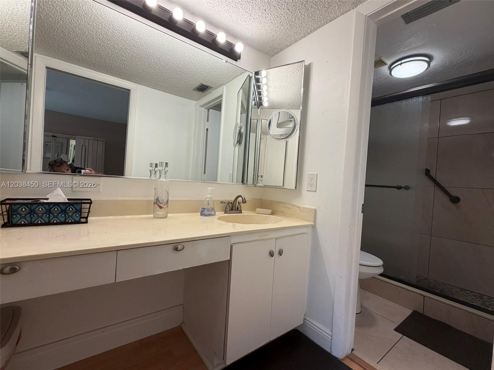 A bathroom features a vanity with a beige countertop and a separate walk-in shower — 4960 E Sabal Palm Blvd # 308, Tamarac FL 33319, TAMARAC, FL