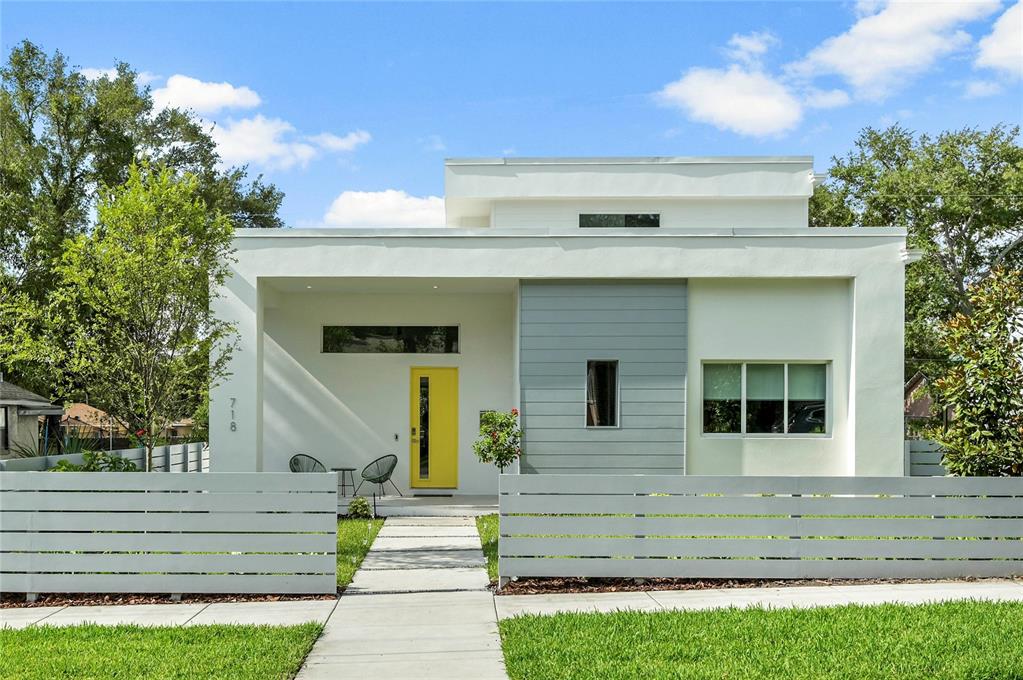 A modern one-story house features a bright yellow front door and a white horizontal fence — 718 14TH AVENUE S, ST PETERSBURG, FL