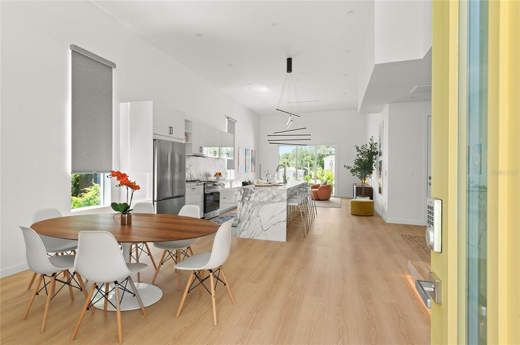 A modern open-concept kitchen and dining area features a marble island and light wood floors — 718 14TH AVENUE S, ST PETERSBURG, FL