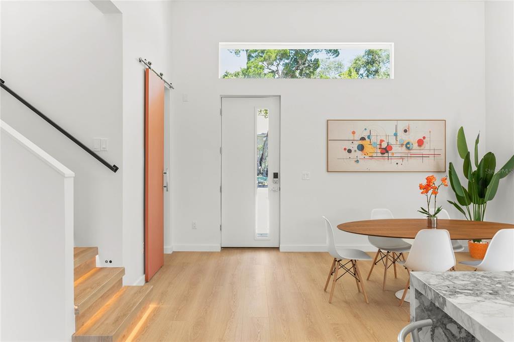 A bright entryway features light wood floors, a modern staircase, and a dining area — 718 14TH AVENUE S, ST PETERSBURG, FL