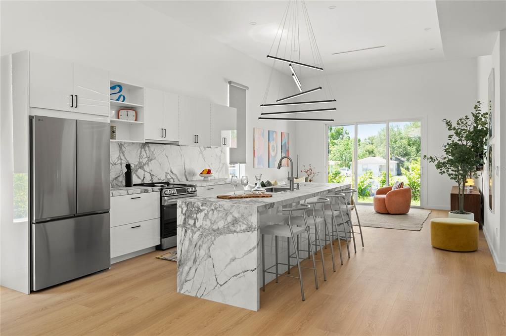 A modern kitchen features a marble waterfall island, white cabinetry, and stainless steel appliances — 718 14TH AVENUE S, ST PETERSBURG, FL