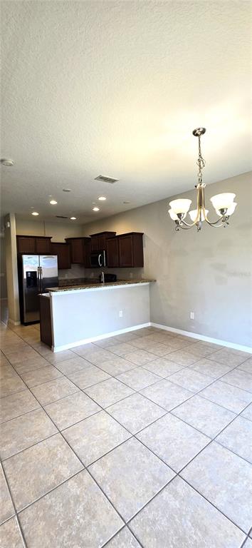 A kitchen with dark wood cabinets and a breakfast bar overlooks a tiled dining area — 10797 SAVANNAH LANDING CIRCLE, ORLANDO, FL