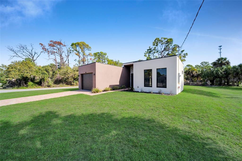 A modern, flat-roofed house with a brown garage and white exterior sits on a lawn — 446 SKYLAND LANE, PORT CHARLOTTE, FL