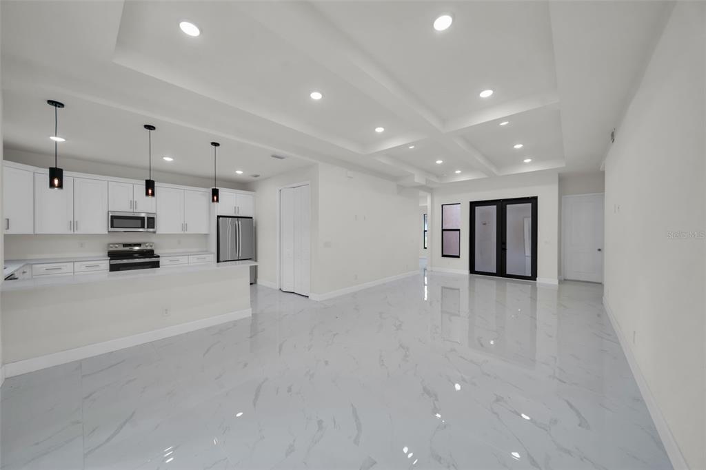 A modern, open-concept kitchen and living area featuring white cabinetry, marble-look tile flooring, and recessed lighting — 446 SKYLAND LANE, PORT CHARLOTTE, FL
