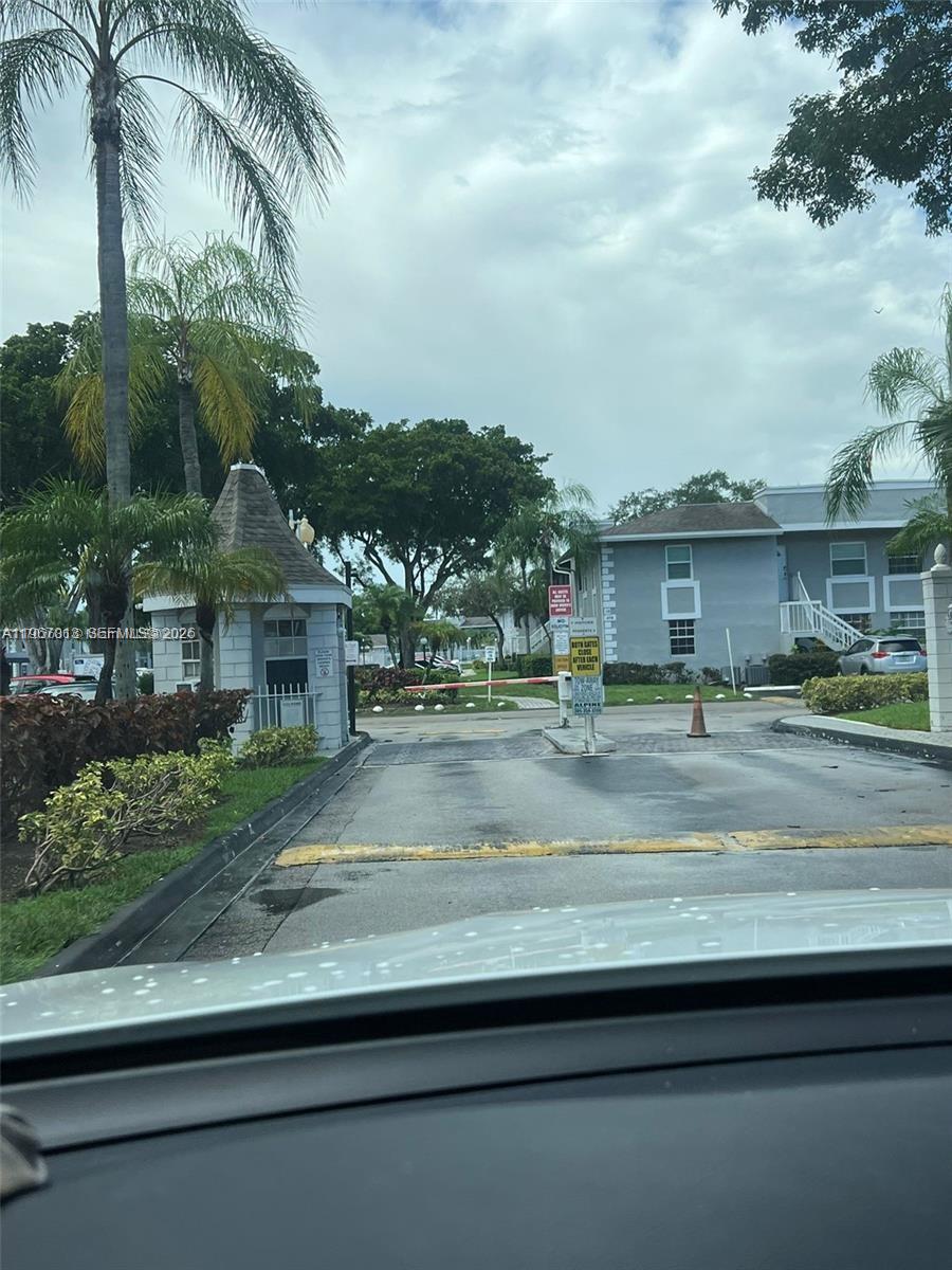 A gated entrance with a guardhouse, palm trees, and a multi-story residential building in the background — 430 NE 210th Cir Ter # 3, Miami FL 33179, MIAMI, FL