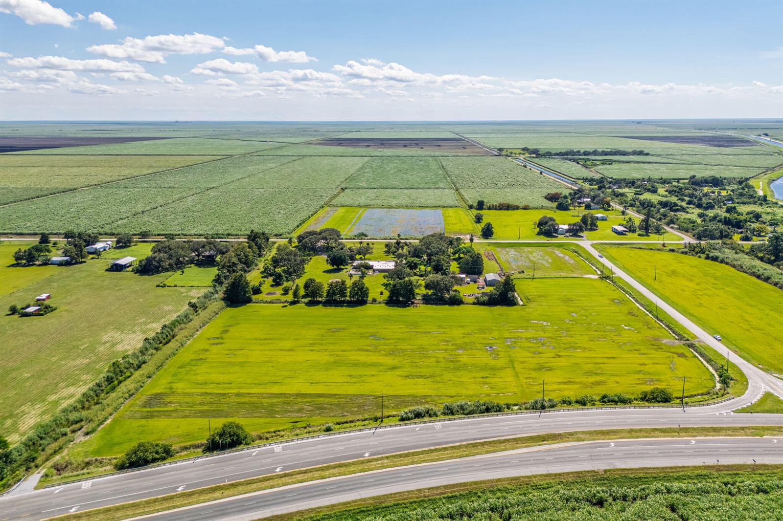 An aerial view shows a rural property with a house, outbuildings, and surrounding agricultural fields — 0 E Corkscrew Boulevard, FL 33440, FL