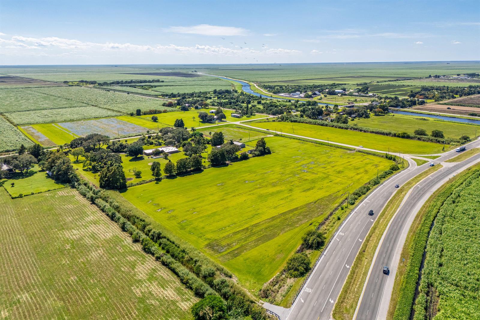 An aerial view shows a rural property with a house, trees, and fields near a highway — 0 E Corkscrew Boulevard, FL 33440, FL