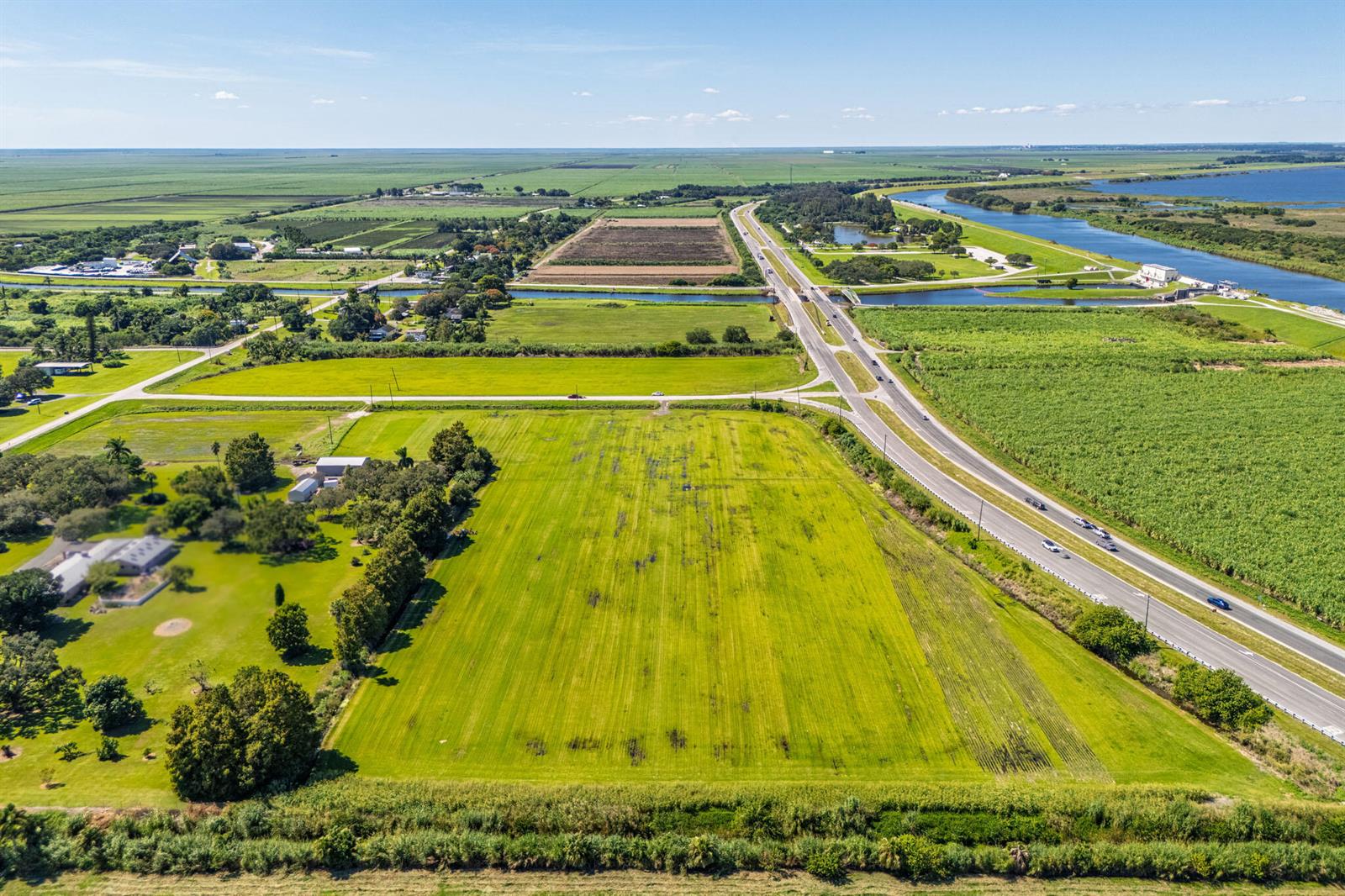 An aerial view shows a large green field adjacent to a highway and farmland — 0 E Corkscrew Boulevard, FL 33440, FL