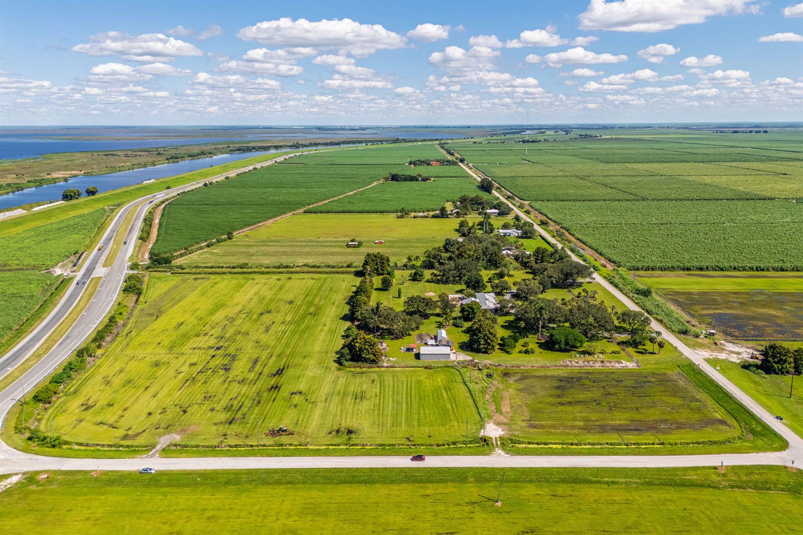 An aerial view shows a rural property with a house, outbuildings, and surrounding agricultural fields — 0 E Corkscrew Boulevard, FL 33440, FL