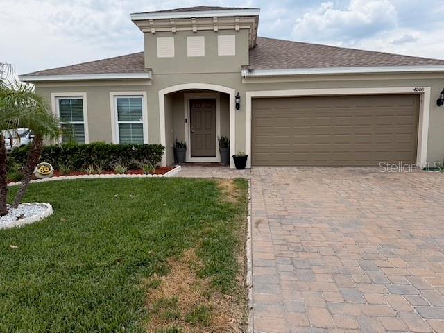 A single-story house with a tan exterior, a paved driveway, and a two-car garage — 4808 ROCKVALE DR, KISSIMMEE, FL
