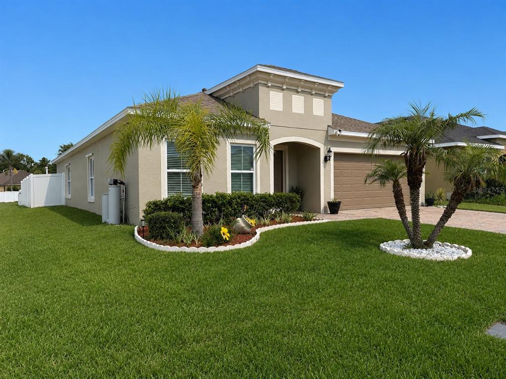 A single-story house with a tan stucco exterior, a two-car garage, and palm trees — 4808 ROCKVALE DR, KISSIMMEE, FL