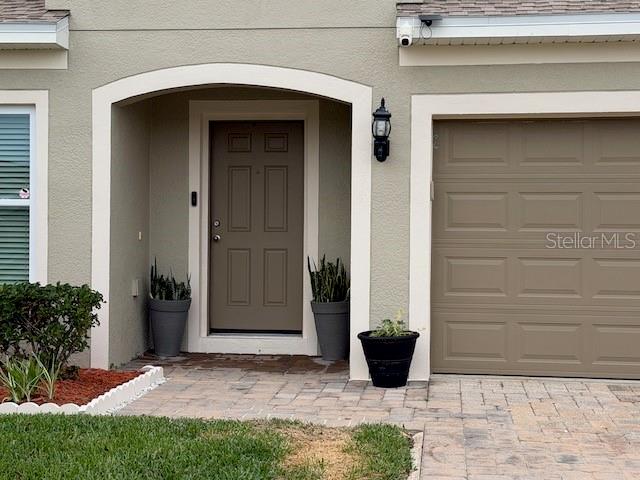 The exterior of a home features a tan front door, garage, and potted plants — 4808 ROCKVALE DR, KISSIMMEE, FL