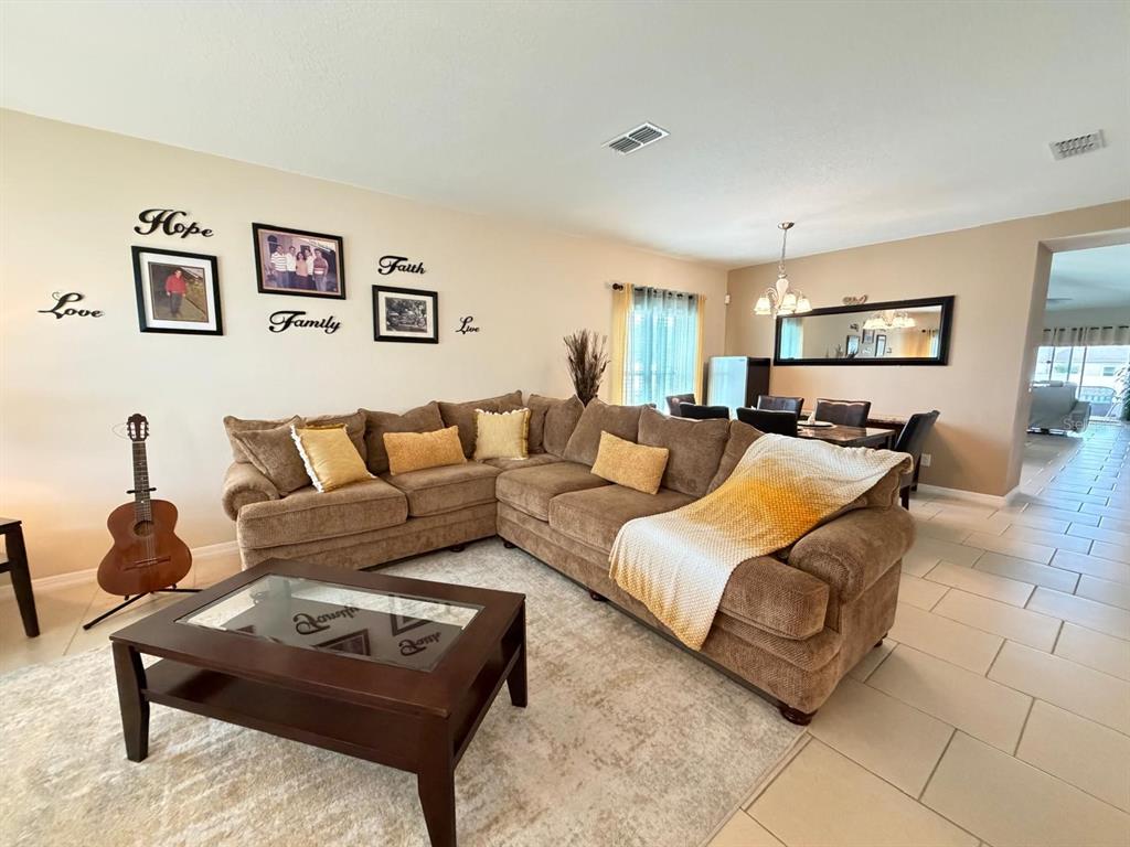 A living room features a large brown sectional sofa, a coffee table, and wall decor — 4808 ROCKVALE DR, KISSIMMEE, FL