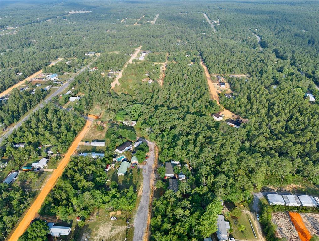 An aerial view shows a rural residential area with scattered houses nestled among dense forest — PINETREE LANE, DEFUNIAK SPRINGS, FL