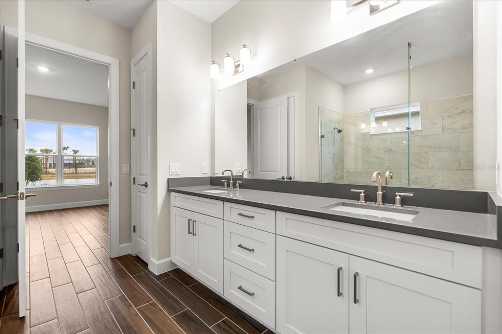 A bathroom features a double vanity with white cabinets, dark countertops, and a large mirror — 5683 NEVIS TERRACE, KISSIMMEE, FL