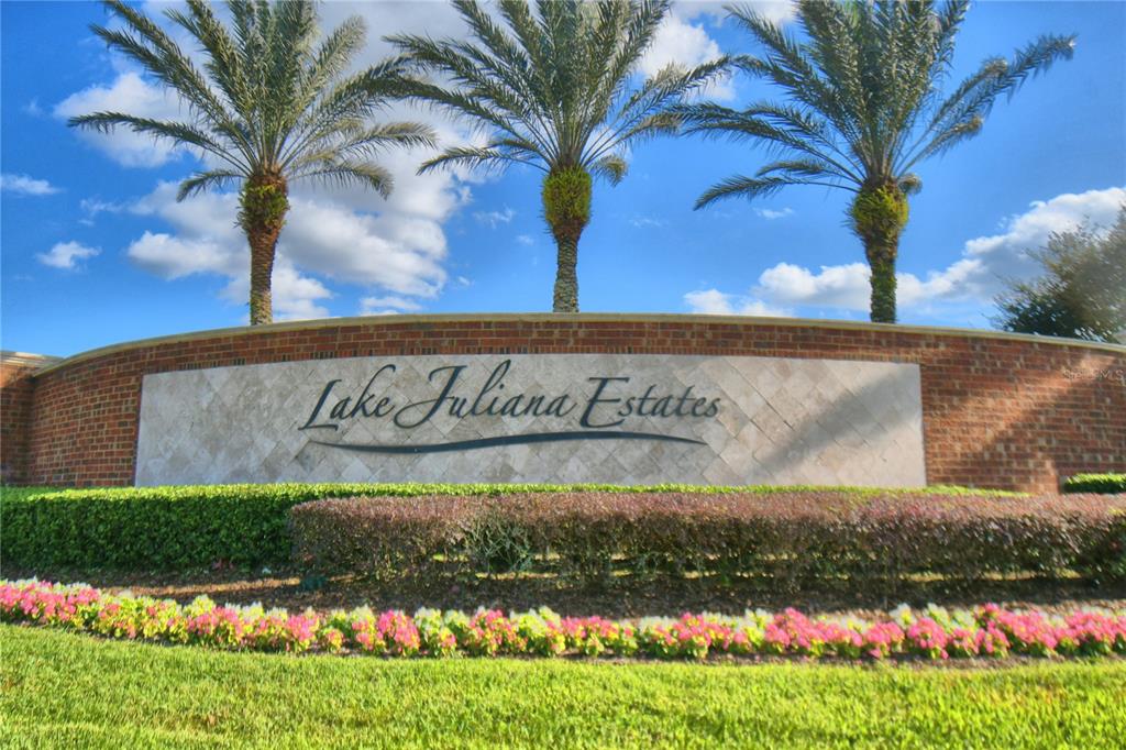A brick entrance sign for Lake Juliana Estates features three palm trees against a blue sky — 4401 JULIANA LAKE DRIVE, AUBURNDALE, FL