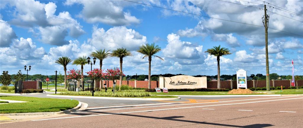 The entrance to Lake Juliana Estates features a brick wall, palm trees, and signage — 4401 JULIANA LAKE DRIVE, AUBURNDALE, FL