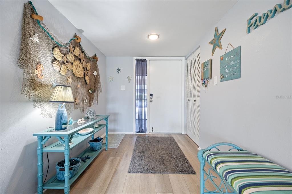 An entryway features a light blue console table, a striped bench, and coastal-themed wall decor — 3 PIRATES LANE UNIT 32A, PUNTA GORDA, FL