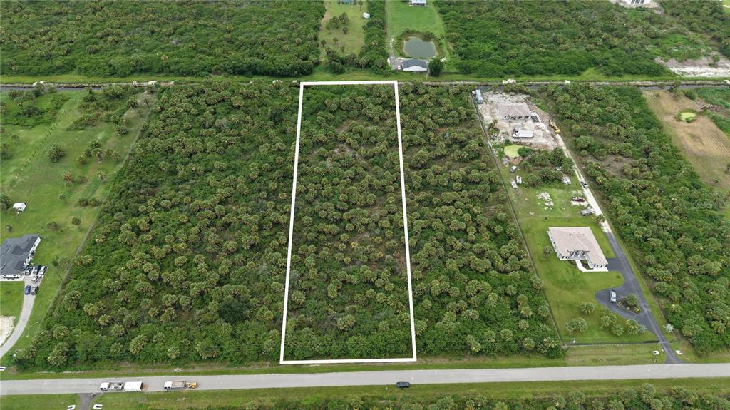 An aerial view shows a rectangular, undeveloped plot of land outlined in white — 39TH AVENUE NW, NAPLES, FL