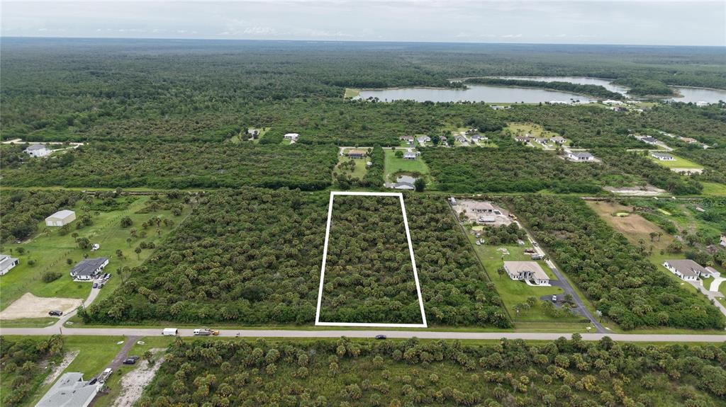 An aerial view shows a rectangular vacant lot outlined in white amidst a wooded landscape — 39TH AVENUE NW, NAPLES, FL