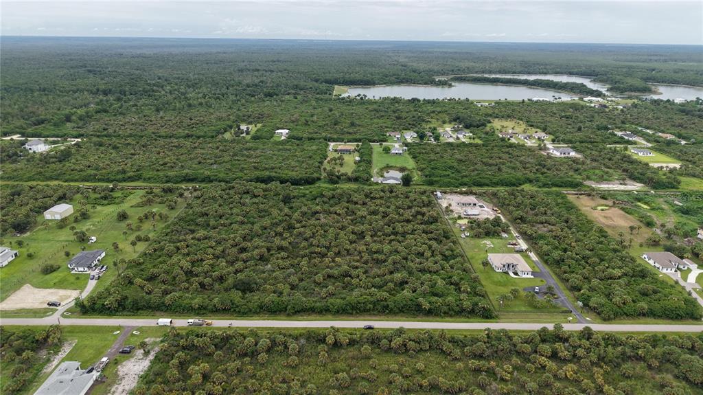 An aerial view shows a large, undeveloped wooded lot situated between several residential properties — 39TH AVENUE NW, NAPLES, FL