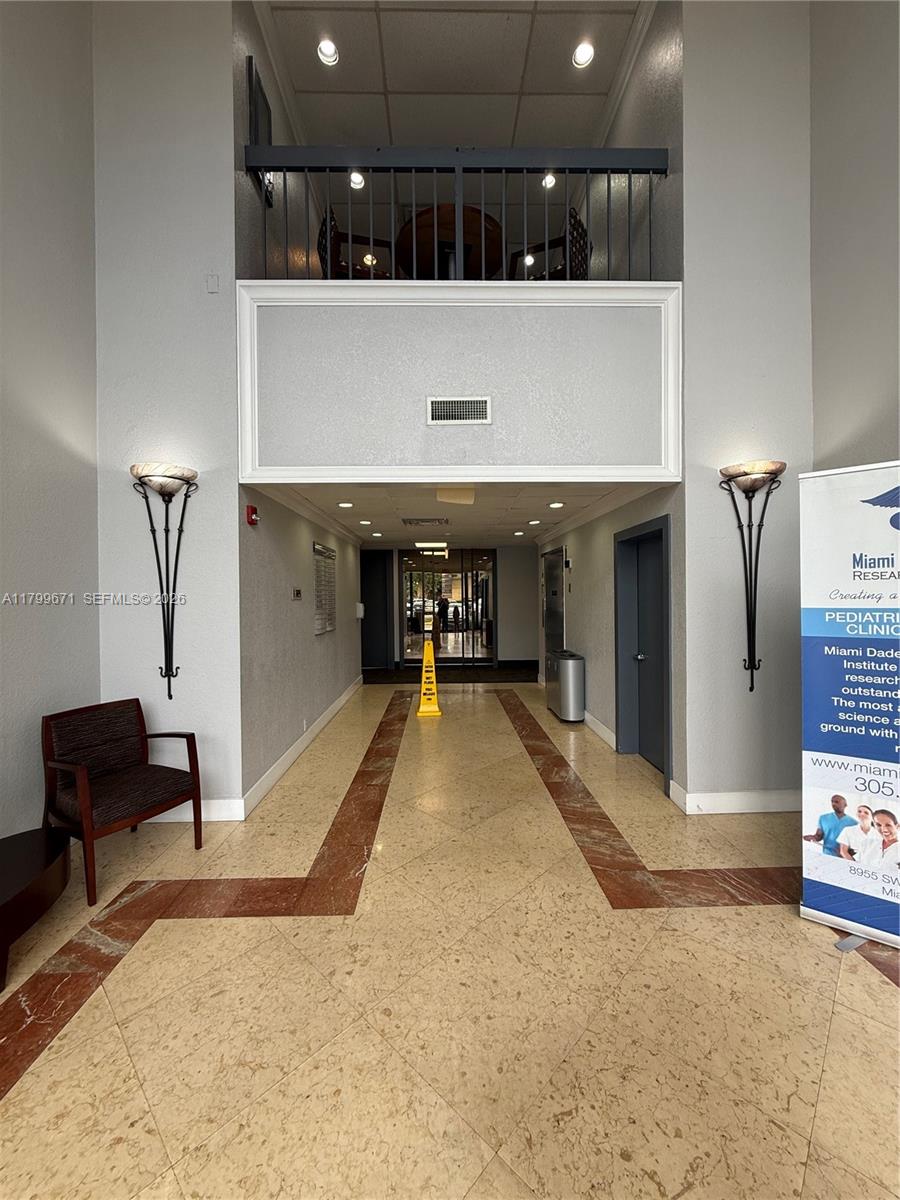 A brightly lit building lobby features tiled floors with a red accent border and wall sconces — 8955 SW 87th Ct # 101, Miami FL 33176, MIAMI, FL