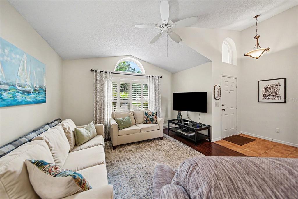 A living room features a vaulted ceiling, a ceiling fan, a television, and two sofas — 2936 MOORCROFT CT, ORLANDO, FL