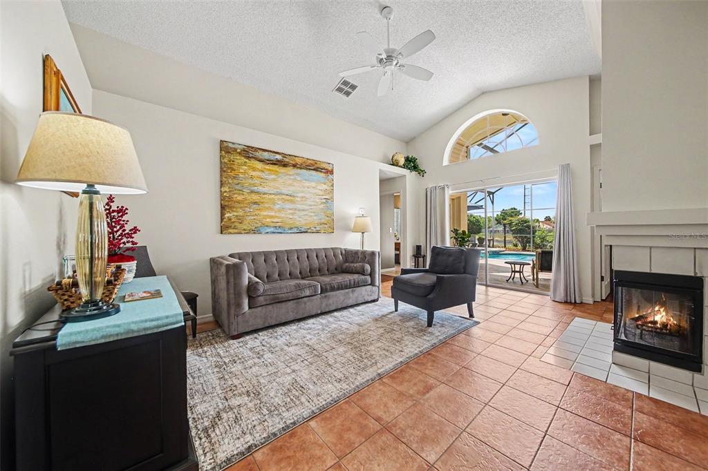 A living room features a fireplace, a grey sofa, tile flooring, and a sliding glass door — 2936 MOORCROFT CT, ORLANDO, FL