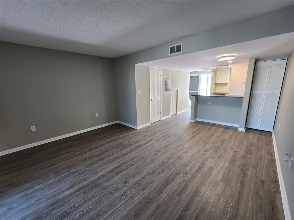 An open-concept living area features grey walls, wood-look flooring, and a kitchen breakfast bar — 701 1ST STREET UNIT 2, INDIAN ROCKS BEACH, FL
