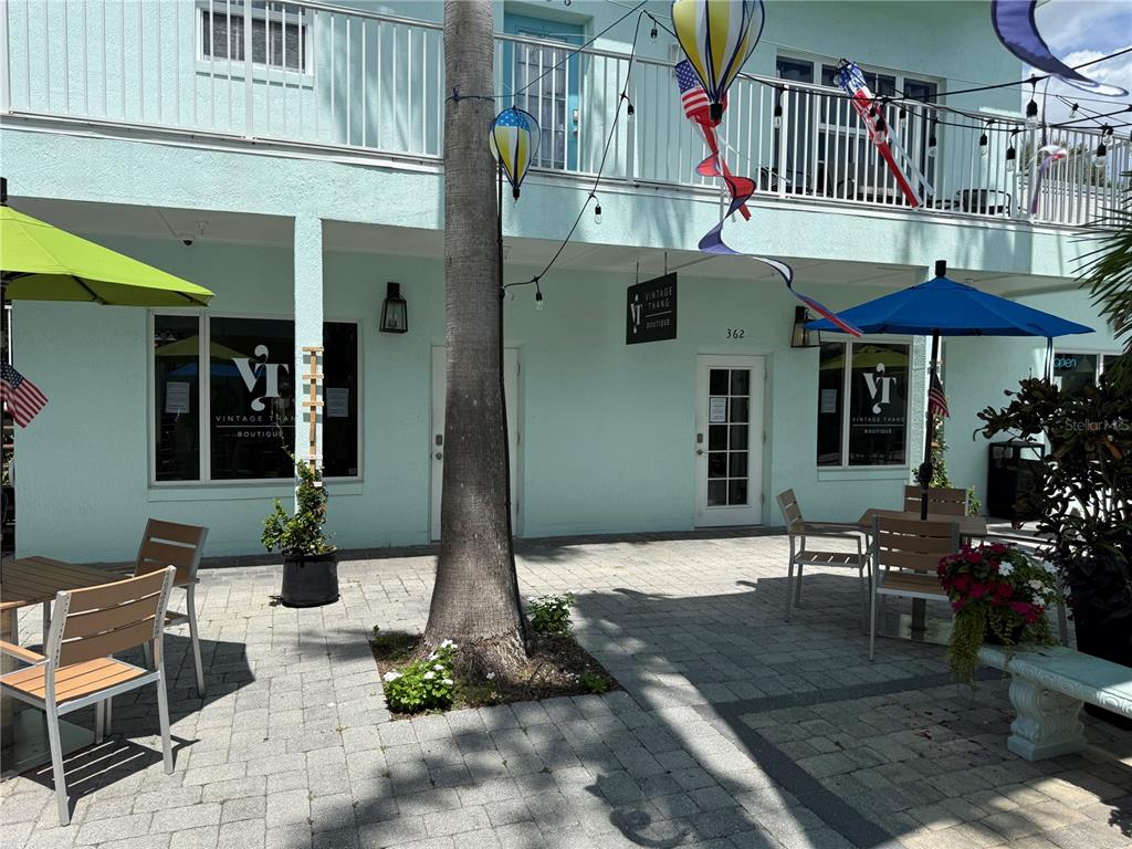 The exterior of a light blue building features a patio with tables, chairs, and umbrellas — 362 FLAGLER AVENUE, NEW SMYRNA BEACH, FL