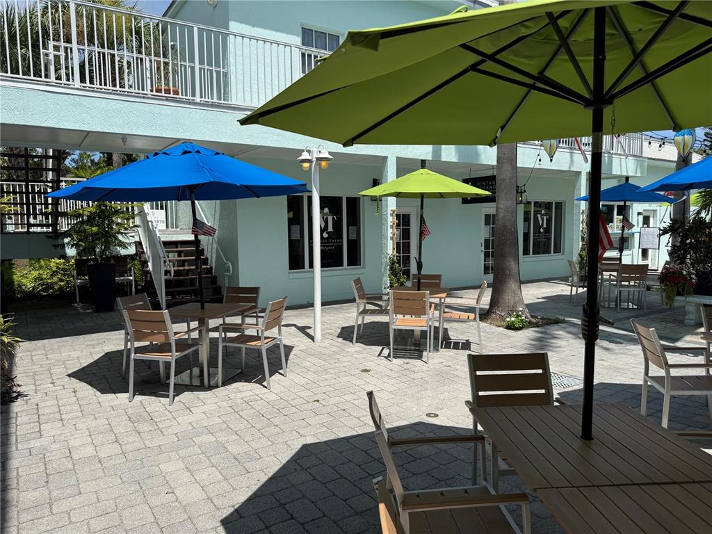 An outdoor patio features several tables with umbrellas and chairs in front of a building — 362 FLAGLER AVENUE, NEW SMYRNA BEACH, FL