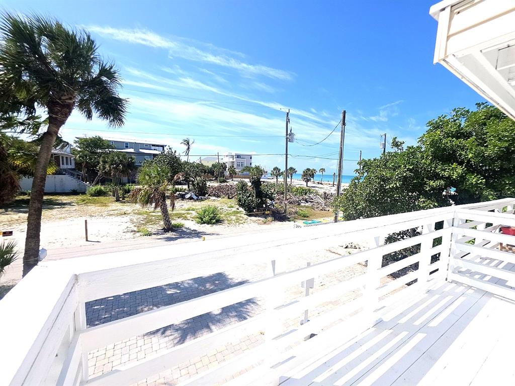 A view of a sandy lot and the ocean from a white wooden balcony — 60 BEACHCOMBER LANE UNIT B, ENGLEWOOD, FL