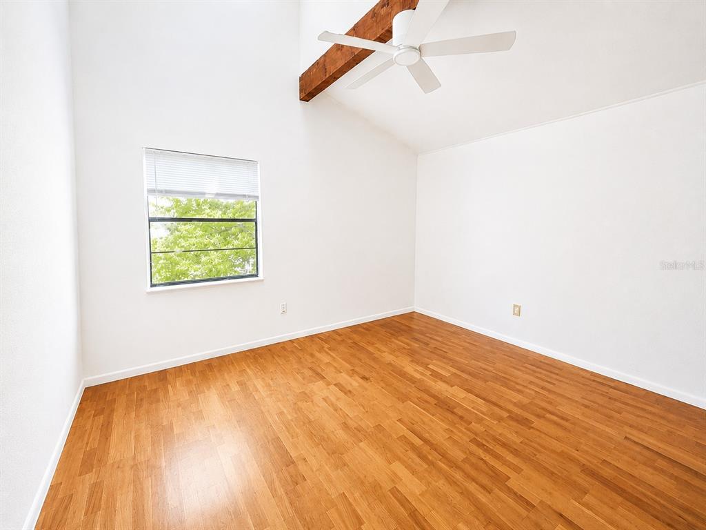 An empty room with wood flooring, white walls, a vaulted ceiling, and a ceiling fan — 60 BEACHCOMBER LANE UNIT B, ENGLEWOOD, FL