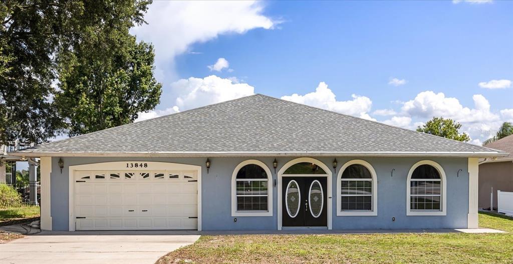 A single-story blue house with a two-car garage and arched windows under a hip roof — 13848 VISTA DEL LAGO BOULEVARD, CLERMONT, FL