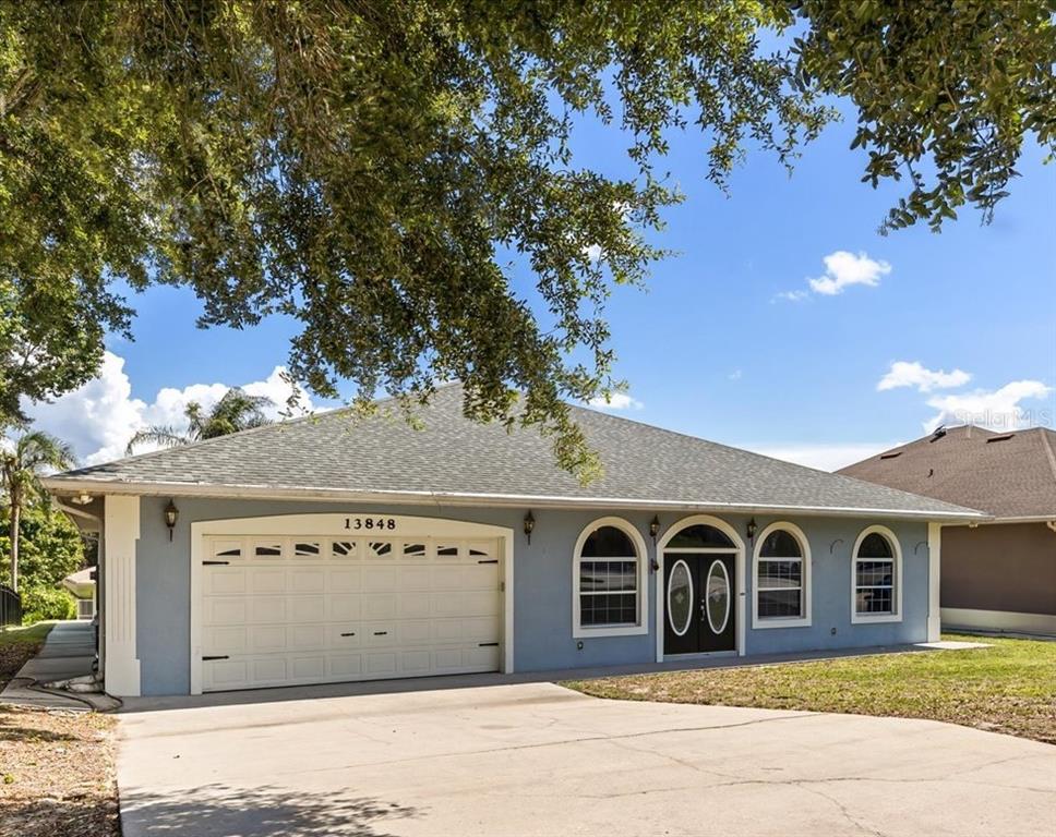 A single-story house with a blue exterior, a two-car garage, and a front entryway — 13848 VISTA DEL LAGO BOULEVARD, CLERMONT, FL