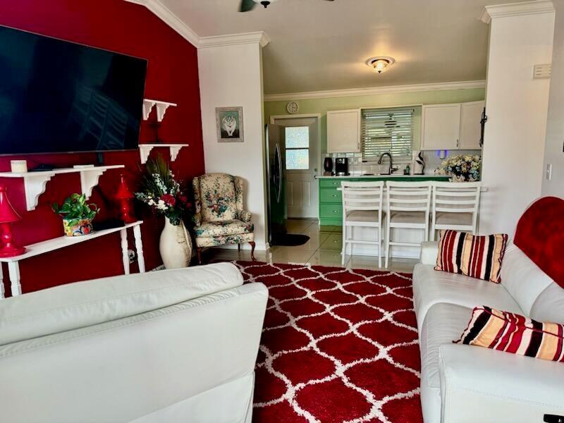 A living room with a red accent wall and rug opens into a green kitchen — 5248 SE 43rd Trace, Okeechobee FL 34974, OKEECHOBEE, FL