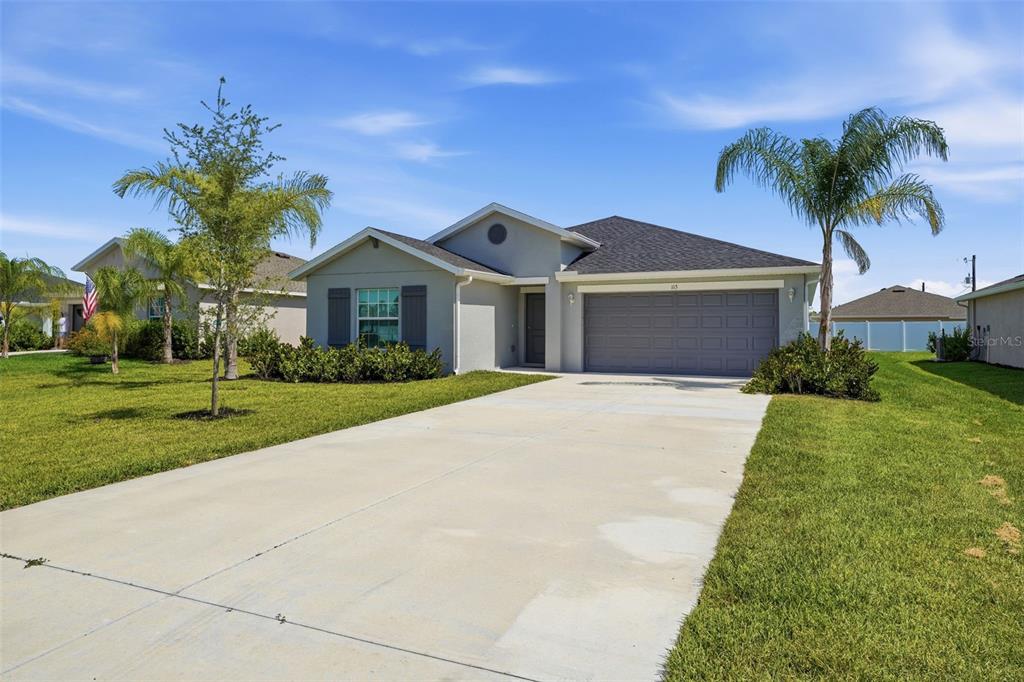 A single-story suburban house with a gray exterior, a two-car garage, and a concrete driveway — 113 LEISURE PLACE, ROTONDA WEST, FL