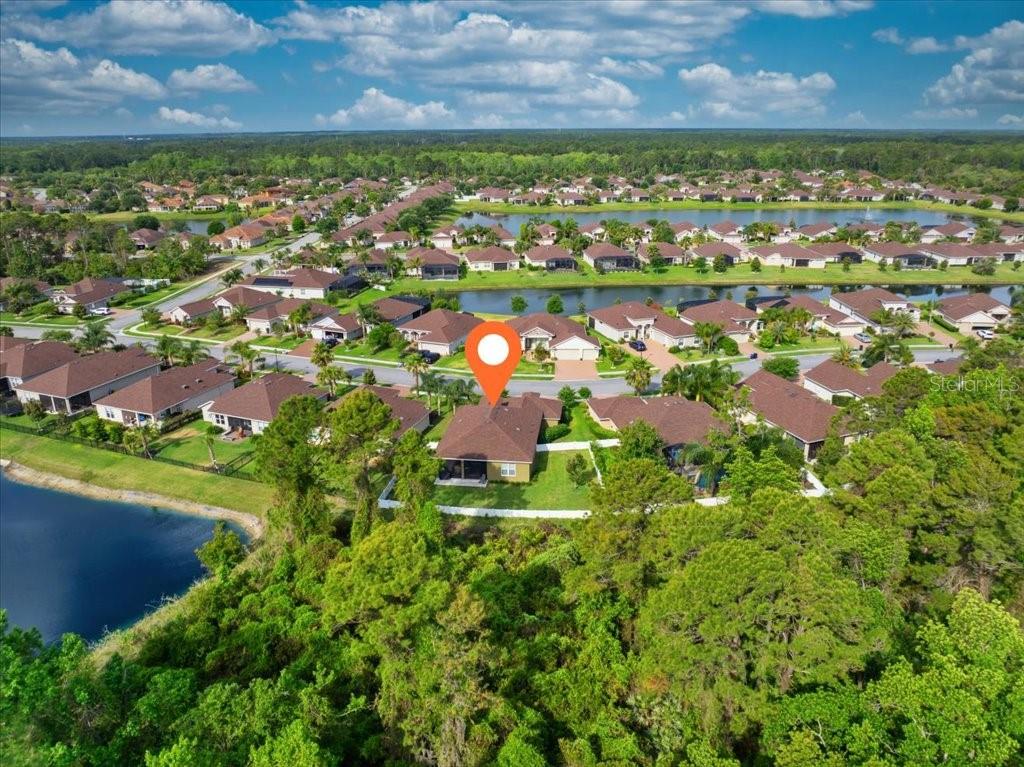 An aerial view shows a single-family home with a fenced backyard bordering a wooded area — 45 GRAHAM WOODS PLACE, PALM COAST, FL