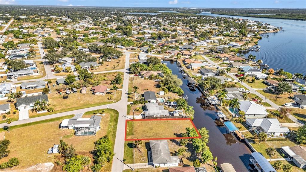 An aerial view shows a vacant rectangular lot outlined in red along a canal — 3334 DOVER DRIVE, PUNTA GORDA, FL