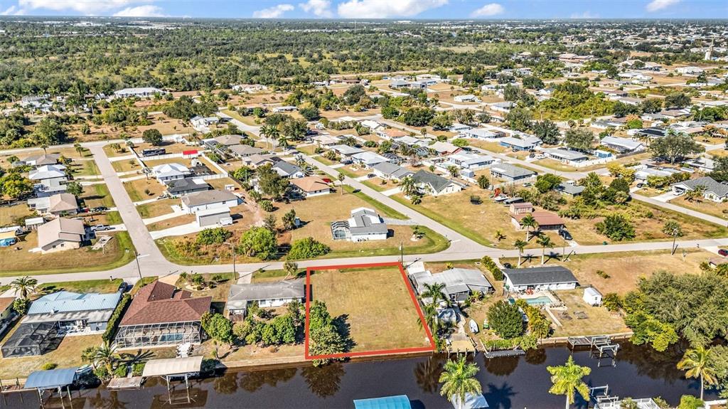 An aerial view shows a vacant waterfront lot outlined in red within a residential neighborhood — 3334 DOVER DRIVE, PUNTA GORDA, FL