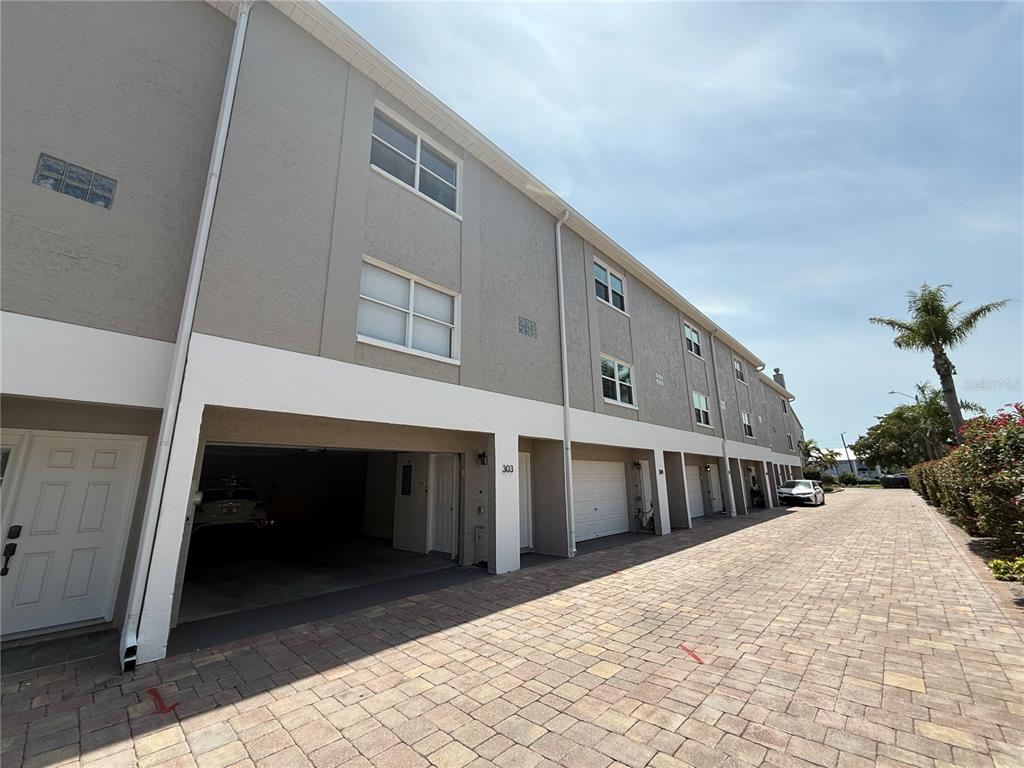 A multi-story townhouse exterior features a ground-level garage and a paved driveway — 1117 PINELLAS BAYWAY S UNIT 303, TIERRA VERDE, FL