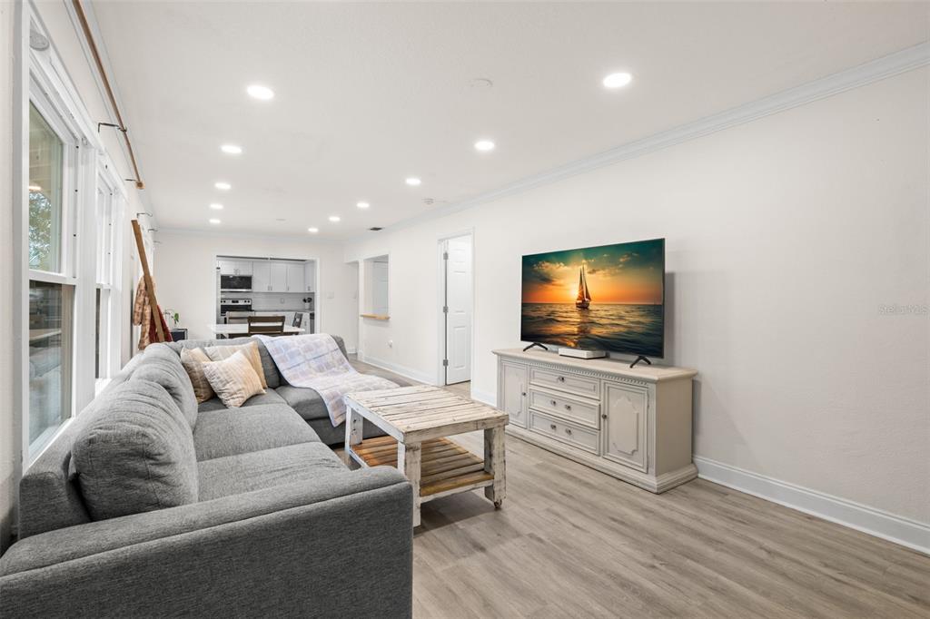 A living room with a gray sectional sofa, a wooden coffee table, and a television — 3822 W EUCLID AVENUE, TAMPA, FL