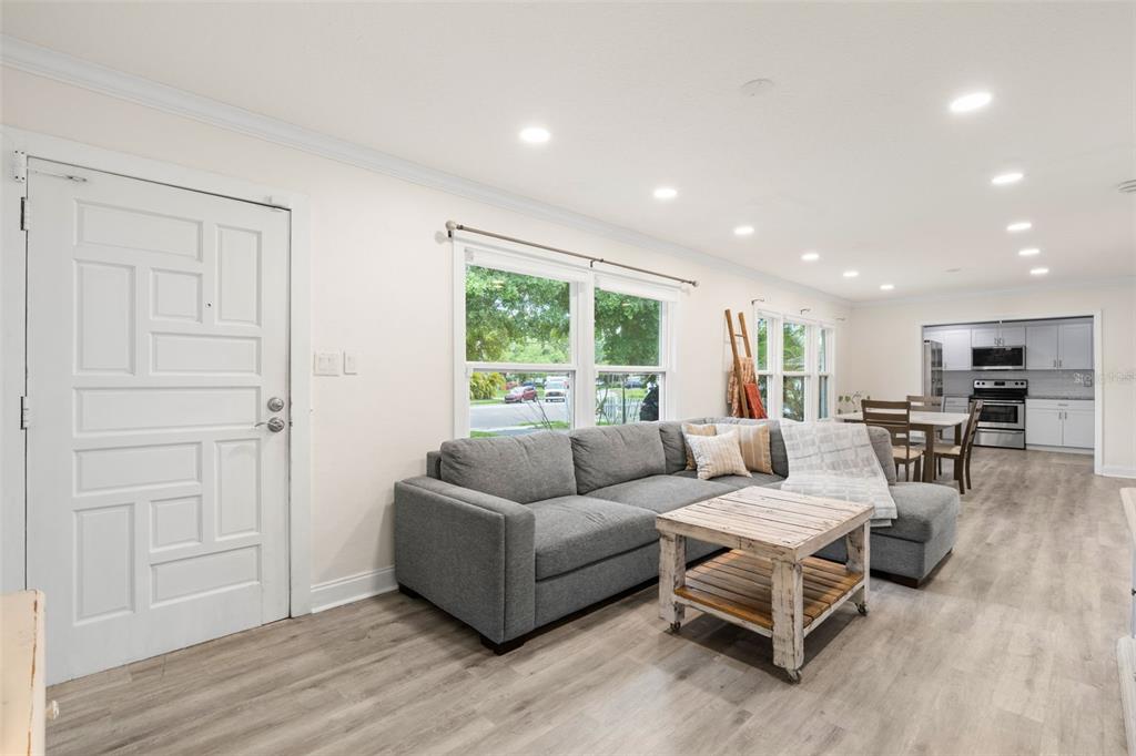 A living room with gray flooring, a sectional sofa, a wooden coffee table, and recessed lighting — 3822 W EUCLID AVENUE, TAMPA, FL