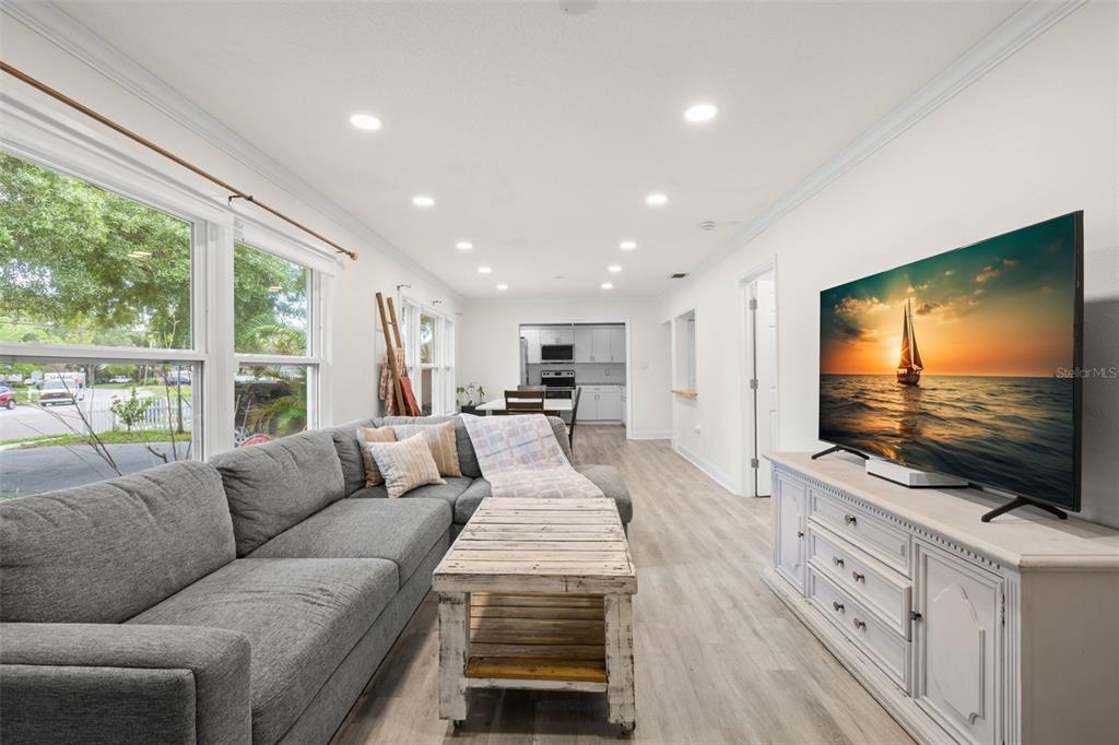 A living room with a gray sectional sofa, rustic coffee table, and a large television — 3822 W EUCLID AVENUE, TAMPA, FL