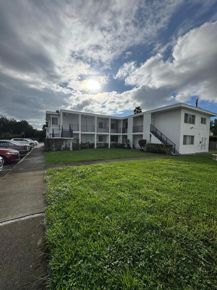 A two-story white apartment building with exterior walkways and stairs sits behind a grassy lawn — 680 NE 88th Ter # 2, Miami FL 33138, MIAMI, FL